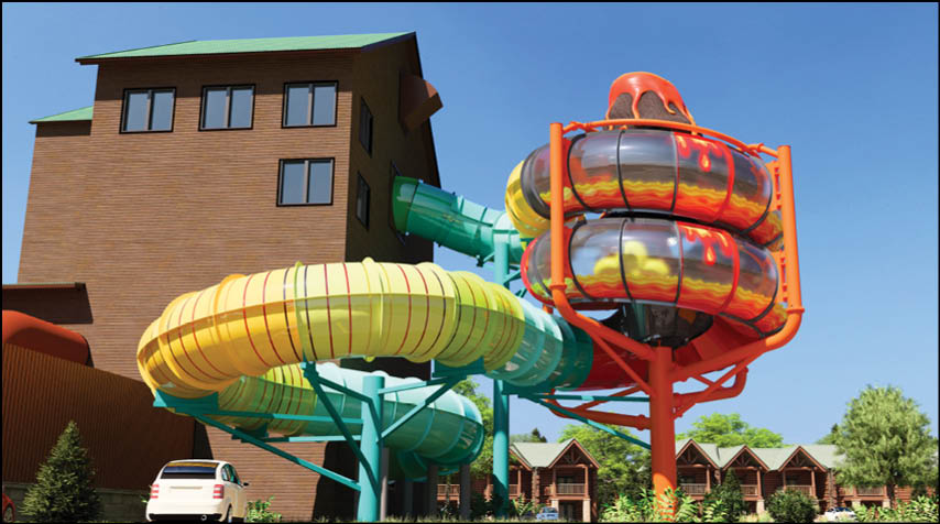 A colorful outdoor water slide structure with multiple twisting tubes is situated next to a building and surrounded by small wooden cabins and trees under a clear blue sky. Description generated by AI