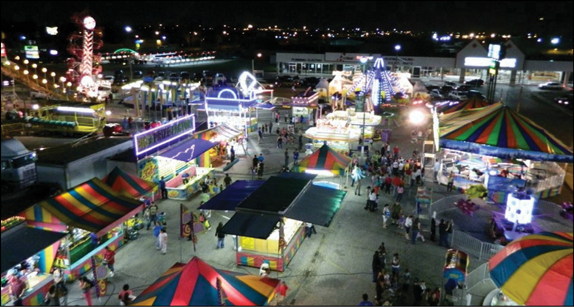 A brightly lit outdoor carnival at night with colorful tents, rides, game booths, and crowds of people walking and enjoying the attractions. Description generated by AI