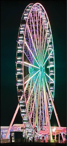 A large, colorful Ferris wheel with a rainbow of colors. Description generated by AI