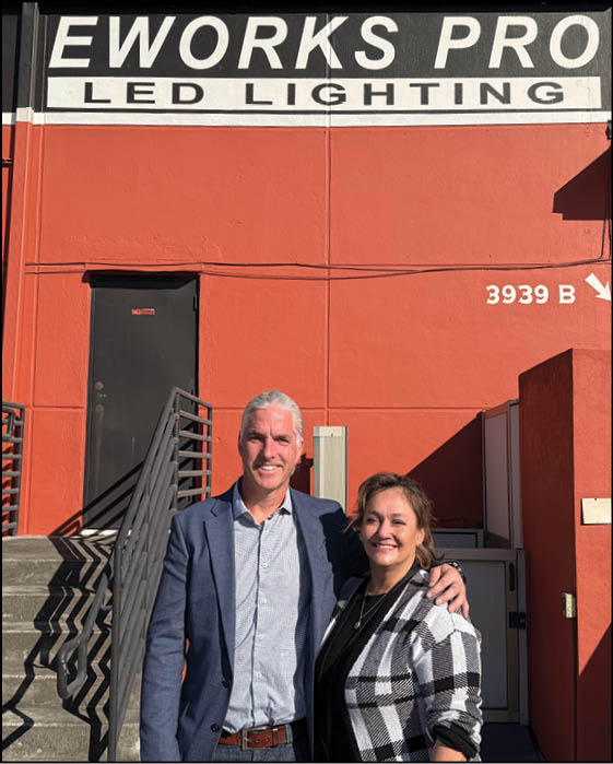 A man and woman standing in front of a red building. Description generated by AI