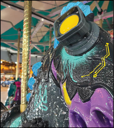 A purple and yellow merry go round horse with a purple nose. Description generated by AI
