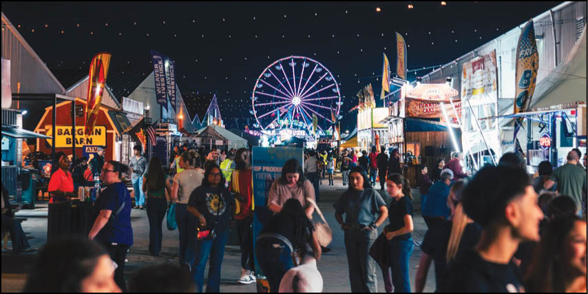 A large group of people are walking around a fairground at night. Description generated by AI