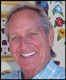 A man is standing in front of a carousel with a sign that says Stinson. Description generated by AI