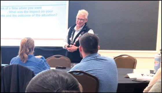 A woman is standing in front of a group of people. Description generated by AI