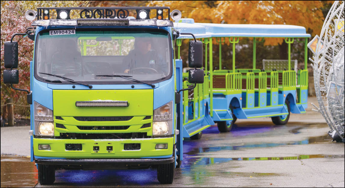 A blue and green bus with a yellow circle on the front. Description generated by AI