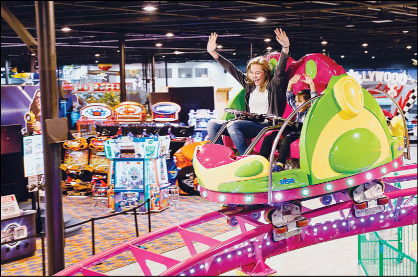 A woman is riding a green and yellow roller coaster. Description generated by AI