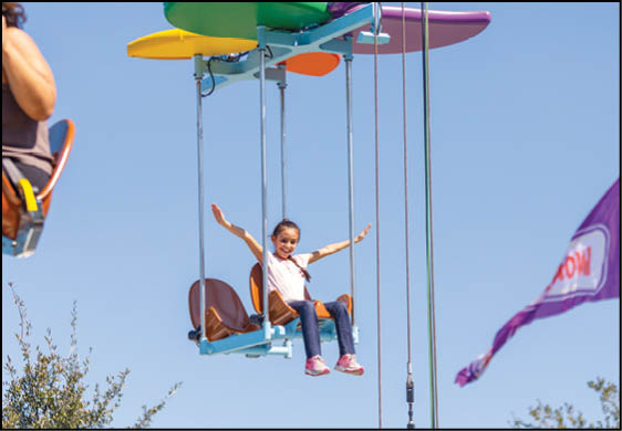 A girl is riding a swing in the air. Description generated by AI