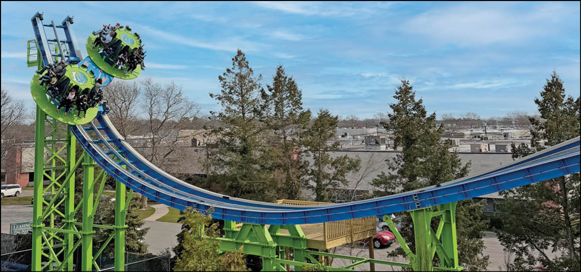 A green and yellow roller coaster with a red and white umbrella in front of it. Description generated by AI