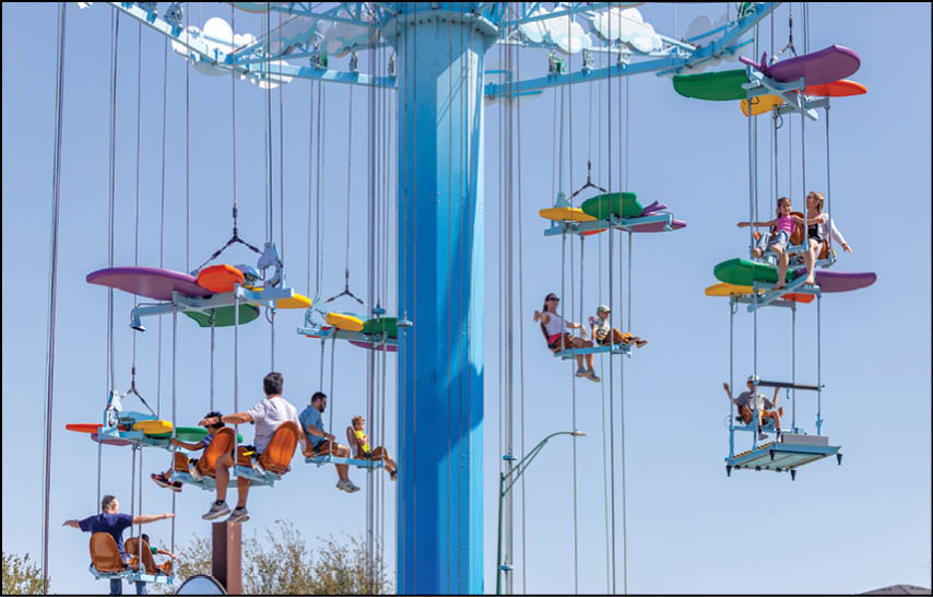 A large blue pole with a group of people riding on swings. Description generated by AI