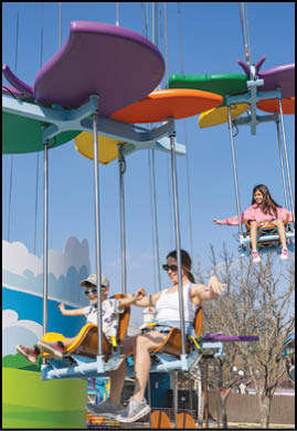 A group of people are riding on a swing ride. Description generated by AI