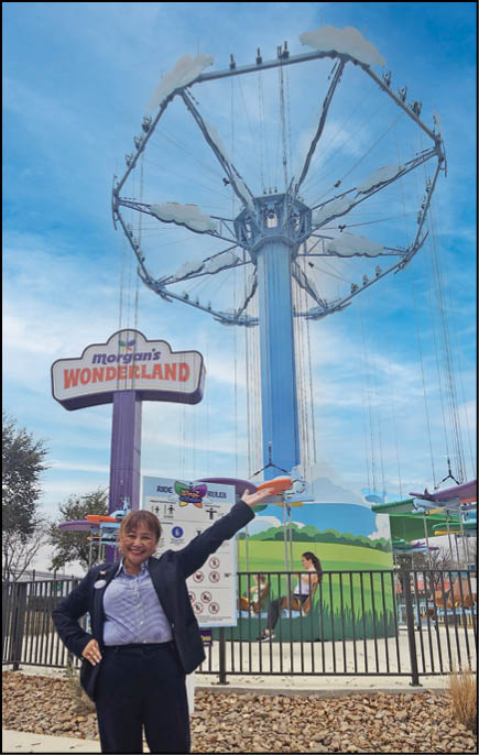 A woman standing in front of a large Ferris wheel. Description generated by AI