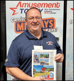 A man holding a magazine with a picture of a roller coaster on the cover. Description generated by AI