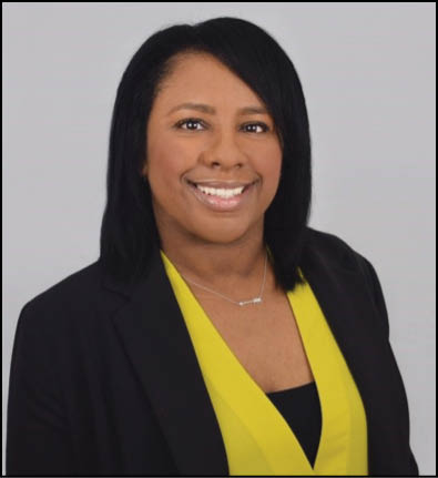 A woman wearing a black jacket and a yellow shirt is smiling. Description generated by AI