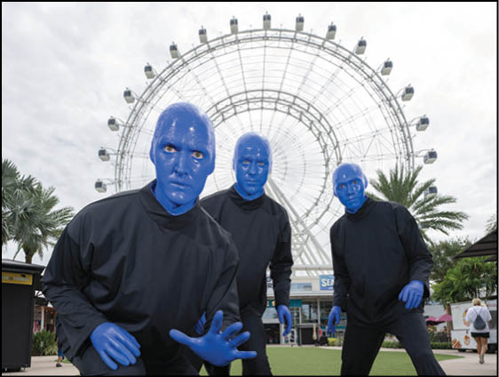 Three men wearing blue face paint and black clothing. Description generated by AI