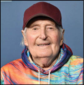 A man wearing a red hat and a colorful hoodie. Description generated by AI
