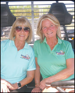 Two women wearing sunglasses and green shirts. Description generated by AI