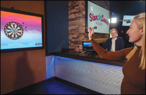 A woman playing a video game with a dart board on the screen. Description generated by AI