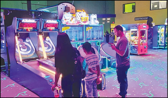 A group of people standing in front of a video game machine. Description generated by AI