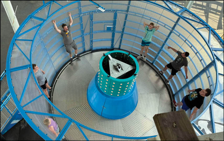 A group of people are on a blue and silver ride. Description generated by AI