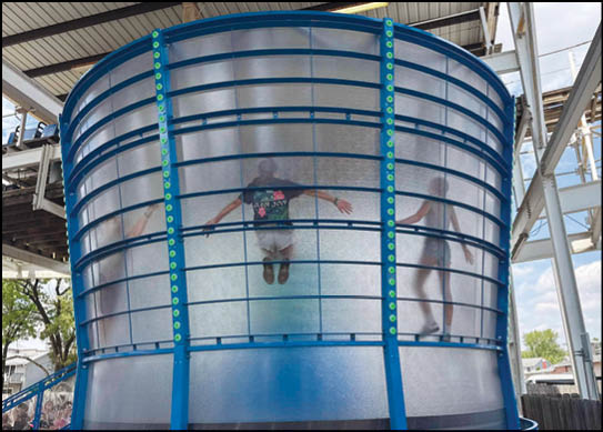 A blue and white water slide with two people riding it. Description generated by AI