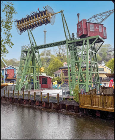 A green and red amusement ride with a red train car. Description generated by AI