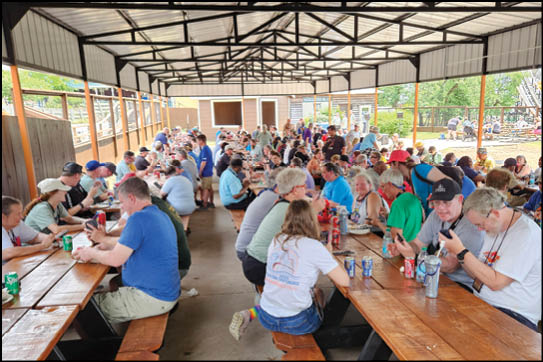 A group of people sitting at picnic tables eating and drinking. Description generated by AI