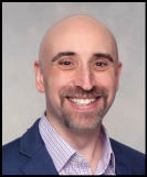A man wearing a white shirt and black jacket. Description generated by AI