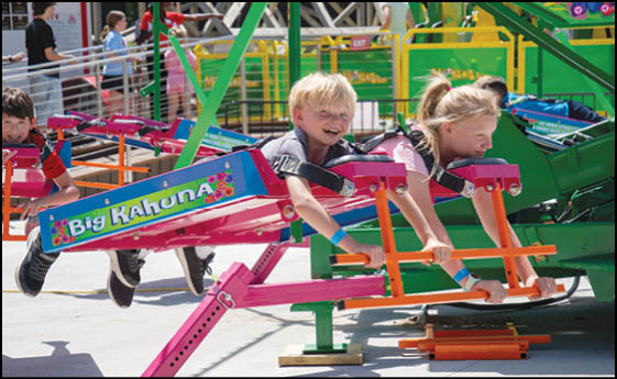 A group of people are sitting in a yellow ride at an amusement park. Description generated by AI