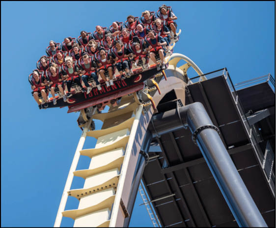 A group of people are sitting in a yellow ride at an amusement park. Description generated by AI