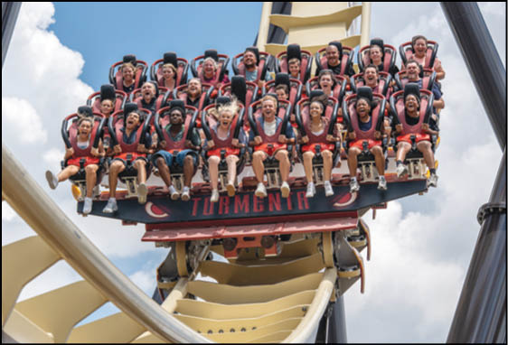 A group of people are sitting in a yellow ride at an amusement park. Description generated by AI