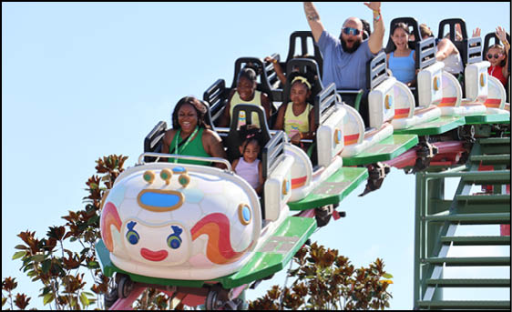 A group of people are sitting in a yellow ride at an amusement park. Description generated by AI