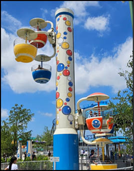 A group of people are sitting in a yellow ride at an amusement park. Description generated by AI