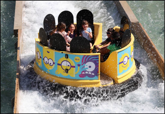 A group of people are sitting in a yellow ride at an amusement park. Description generated by AI