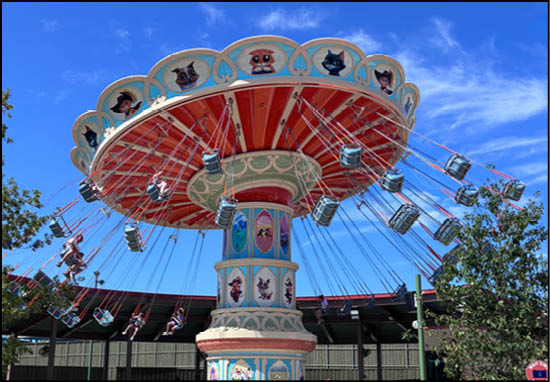 A group of people are sitting in a yellow ride at an amusement park. Description generated by AI