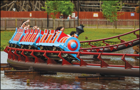 A group of people are sitting in a yellow ride at an amusement park. Description generated by AI