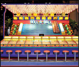 An arcade game called Roll-A-Ball with stools lined up in front and colorful stuffed animal prizes displayed inside. Description generated by AI