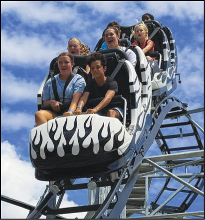 A group of people are sitting in a yellow ride at an amusement park. Description generated by AI