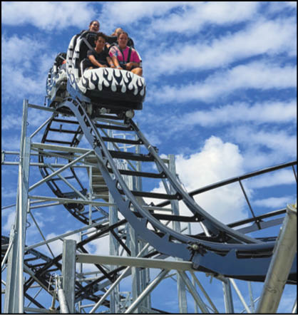 A group of people are sitting in a yellow ride at an amusement park. Description generated by AI
