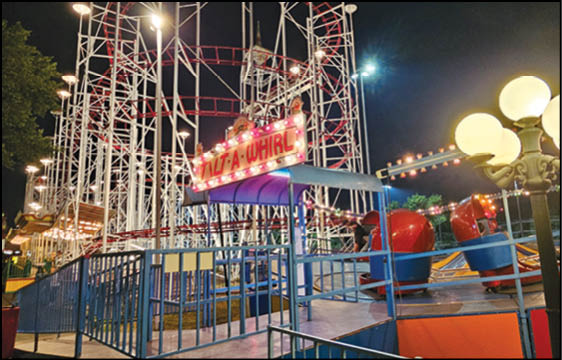 A group of people are sitting in a yellow ride at an amusement park. Description generated by AI