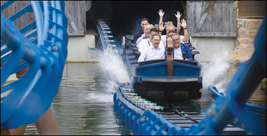 A group of people are sitting in a yellow ride at an amusement park. Description generated by AI
