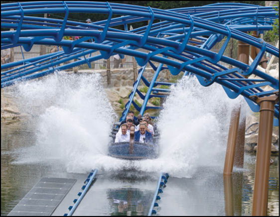 A group of people are sitting in a yellow ride at an amusement park. Description generated by AI