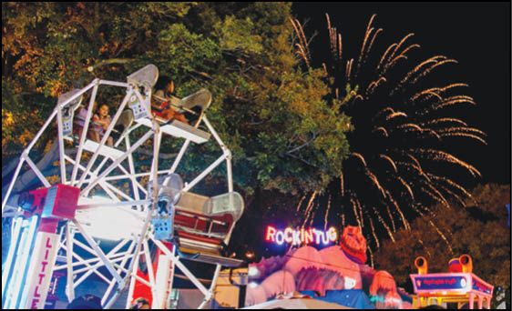 Two men standing in front of a carnival sign. Description generated by AI