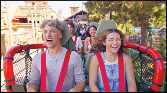 A group of people are sitting in a yellow ride at an amusement park. Description generated by AI