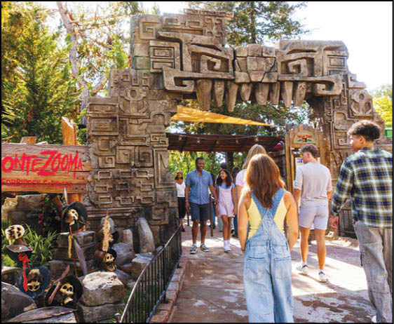 A group of people are sitting in a yellow ride at an amusement park. Description generated by AI