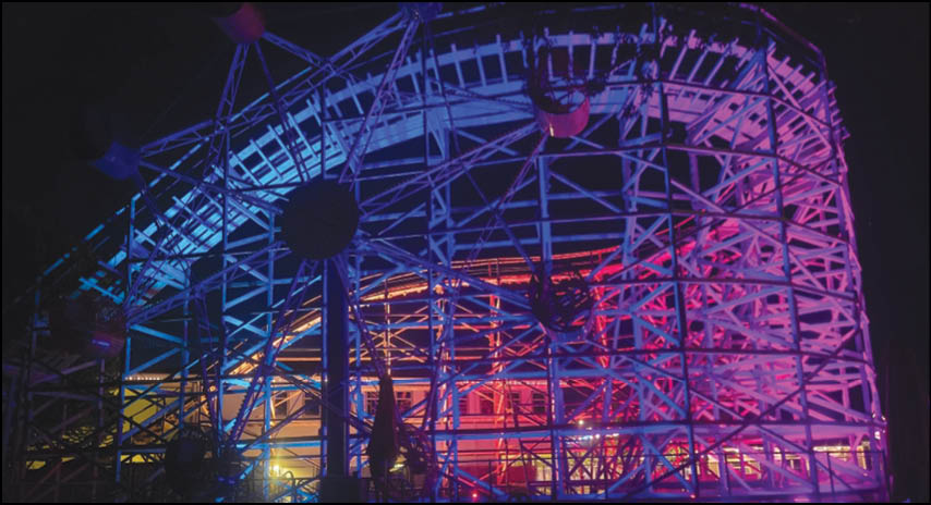 A group of people are sitting in a yellow ride at an amusement park. Description generated by AI