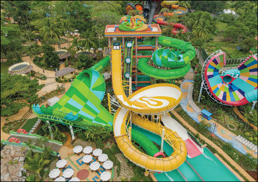 A colorful water park features multiple large twisting water slides surrounded by lush greenery and seating areas. Description generated by AI